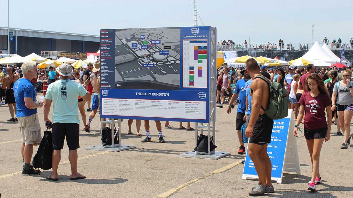 Large wayfinding sign with an event map, surrounded by event participants.