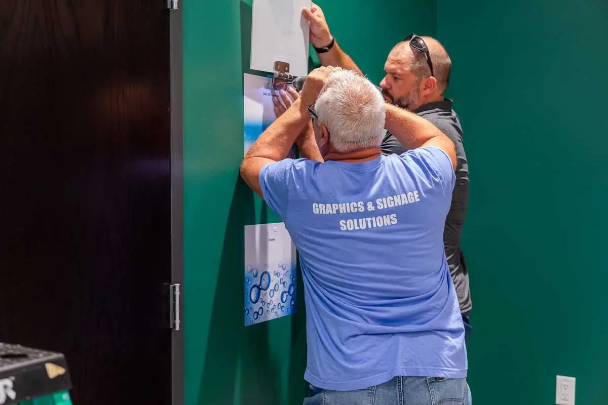 CFR Engines wall graphics being secured by two BPI Color installation team members, emphasizing hands-on installation.