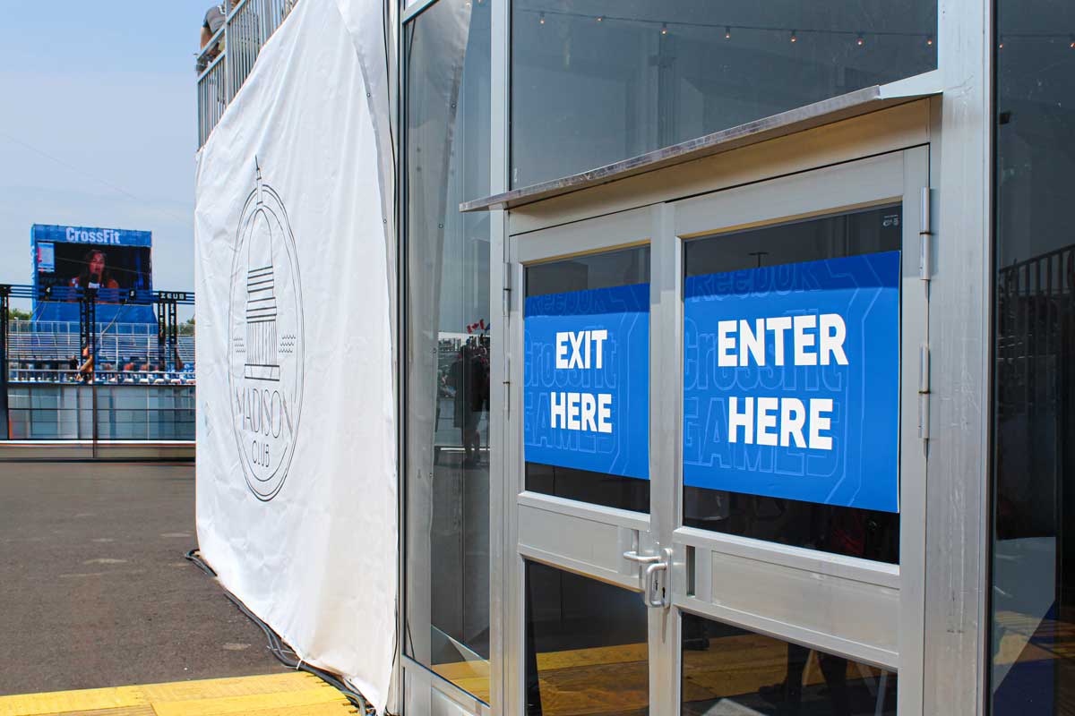 Custom "EXIT HERE" signage displayed on exterior building doors. A large banner with a design for Madison, Wisconsin is hanging to the left.