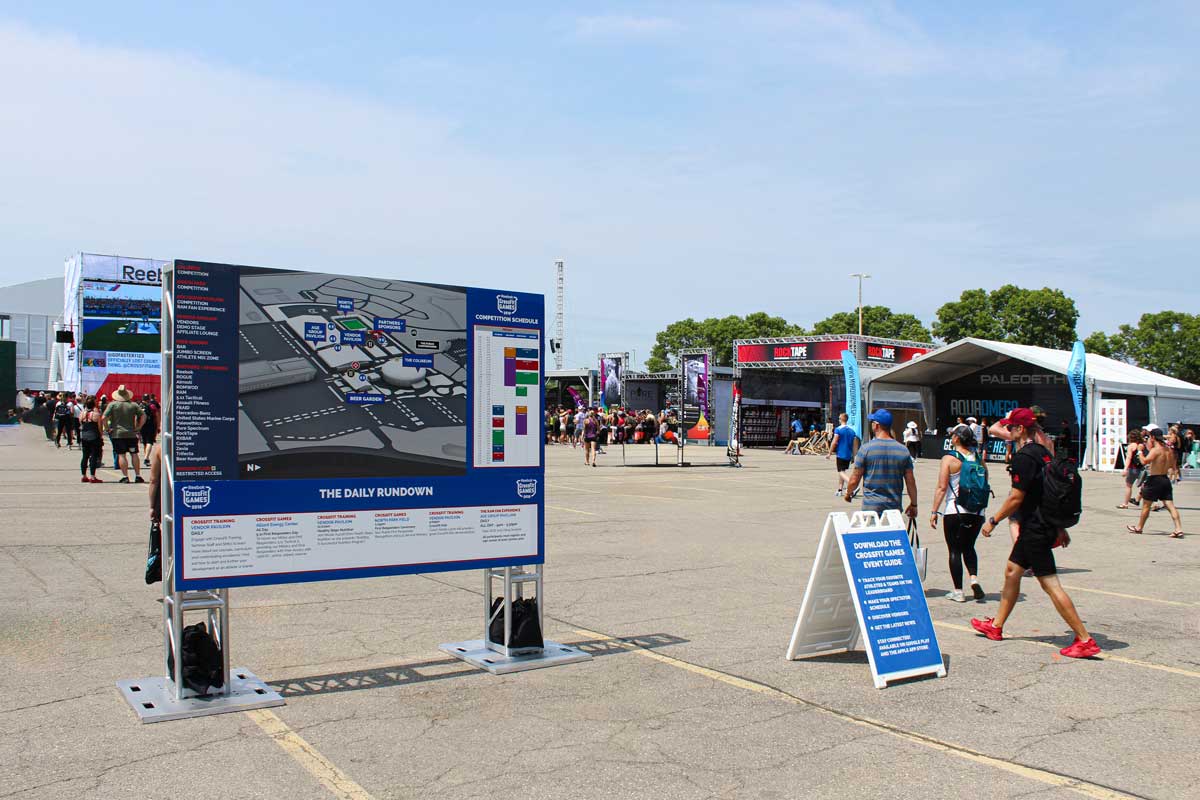 Wayfinding signage with an event map in the middle of a repurposed parking lot with event guests walking around it.