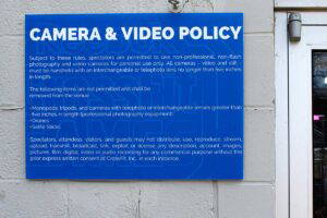 Blue rectangular sign displaying camera and video rules.