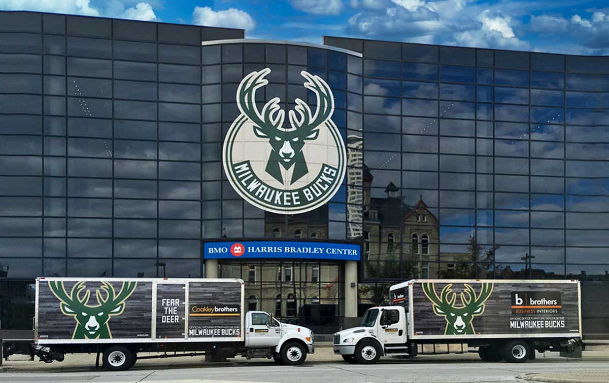 Two large semi-trucks with custom graphics parked in front of a building.