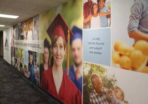 Large adhesive wall fabric that runs the length of a hallway with a custom graphic collage showing people in graduation caps and gowns.