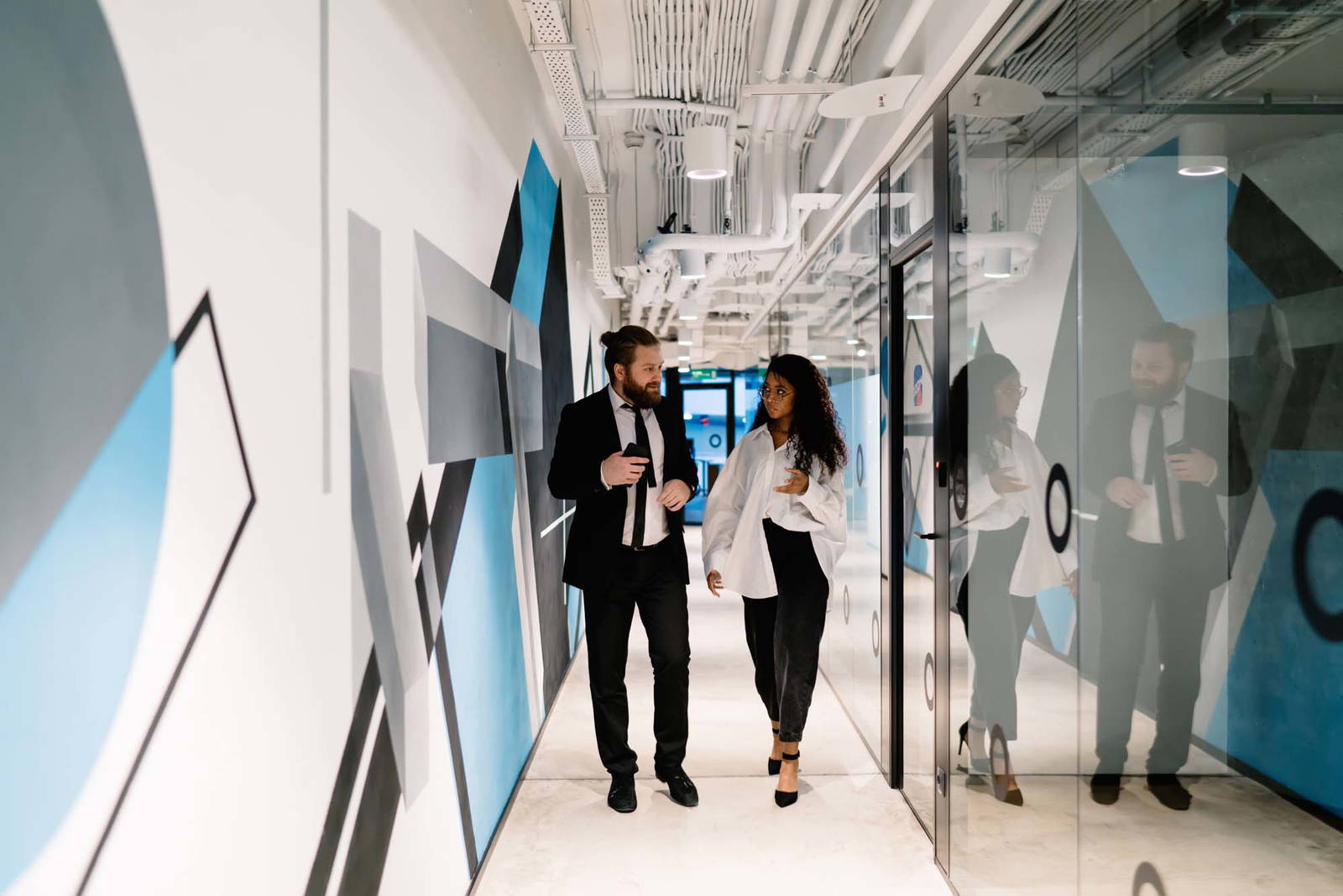 Two office staff walking down a hallway decorated with wall graphics.