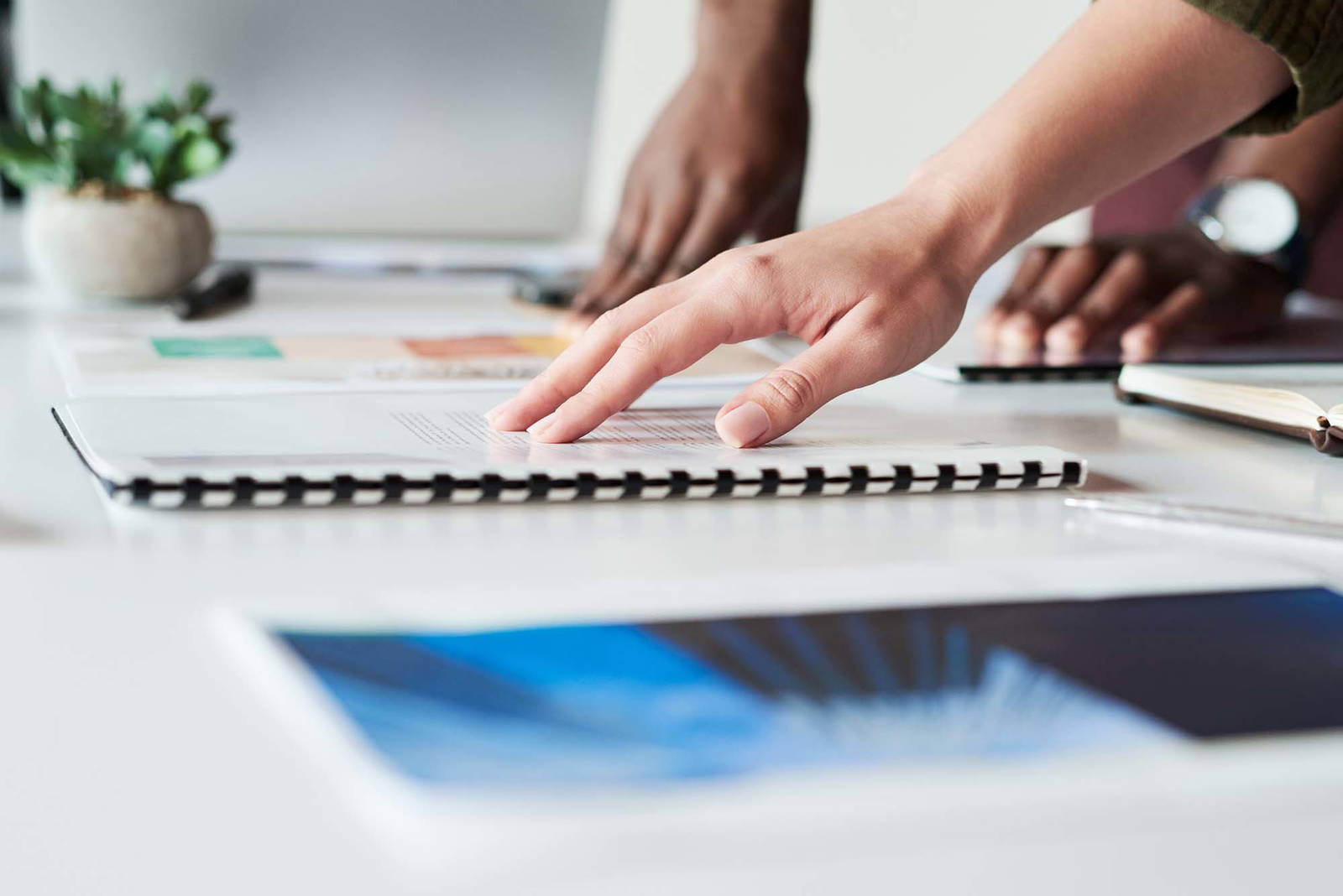 Hands of two design staff working on print materials.
