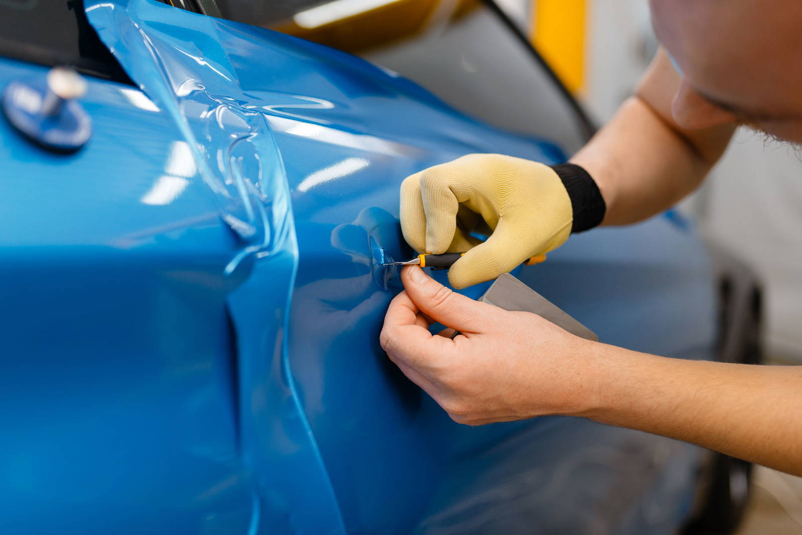 Person applying a blue vehicle wrap.