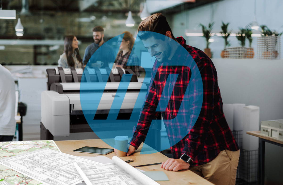 Man working in an office with a large HP printer in the background.