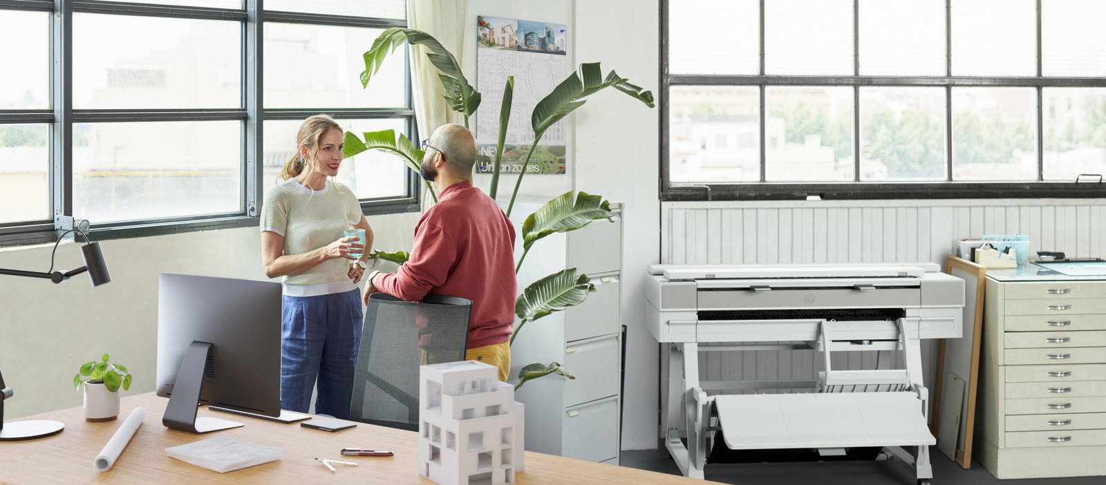 Male and female architects talking in front of an HP DesignJet XT950