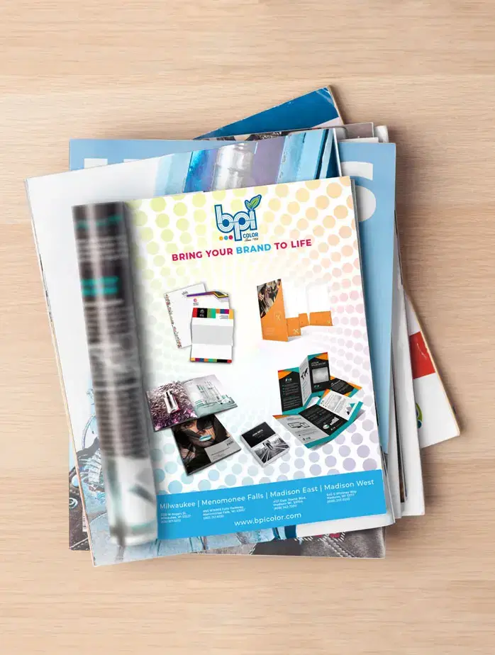 A stack of magazines on a wood table with a BPI Color advertisement showing.