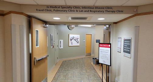 View of a hallway with Wayfinding signage through a set of wooden double doors at a hospital.