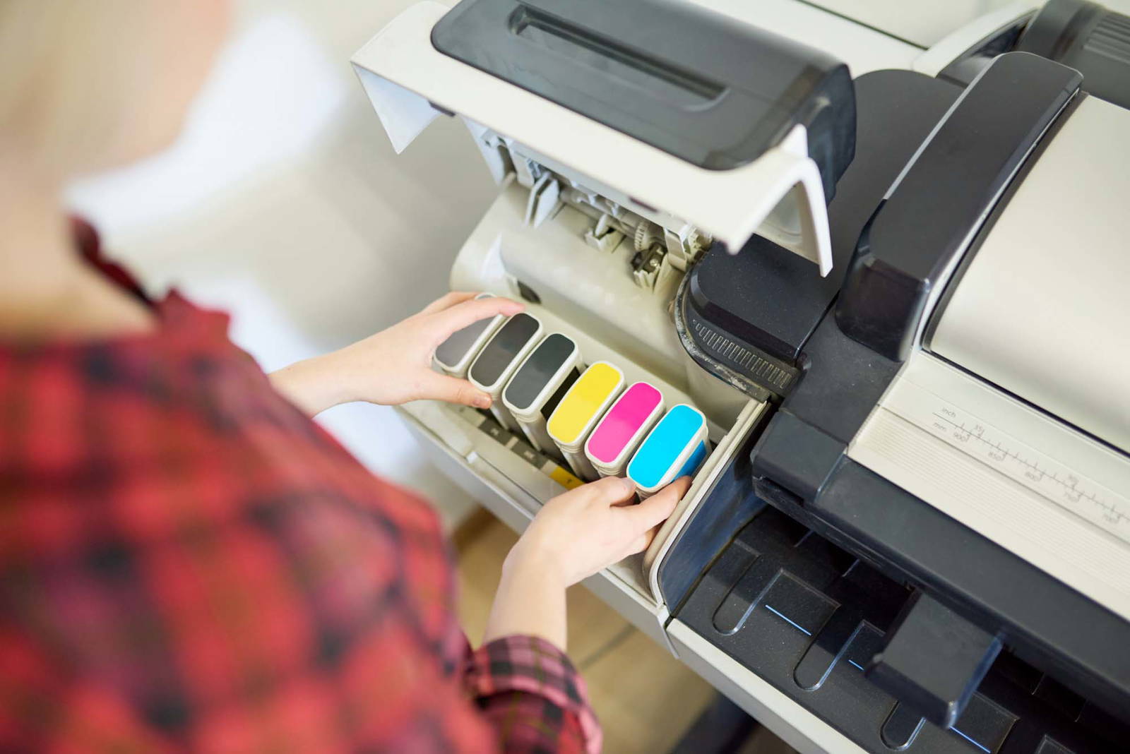 Person installing new ink cartridges into an office computer.
