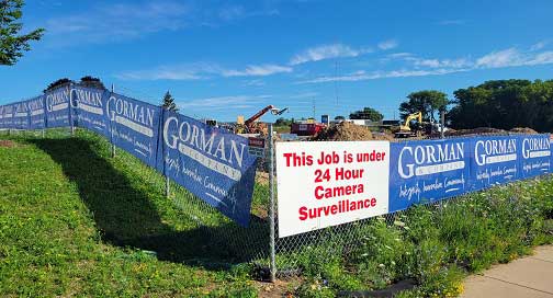April 2025 Newsletter 6 Mesh banners hanging on a chain link fence.