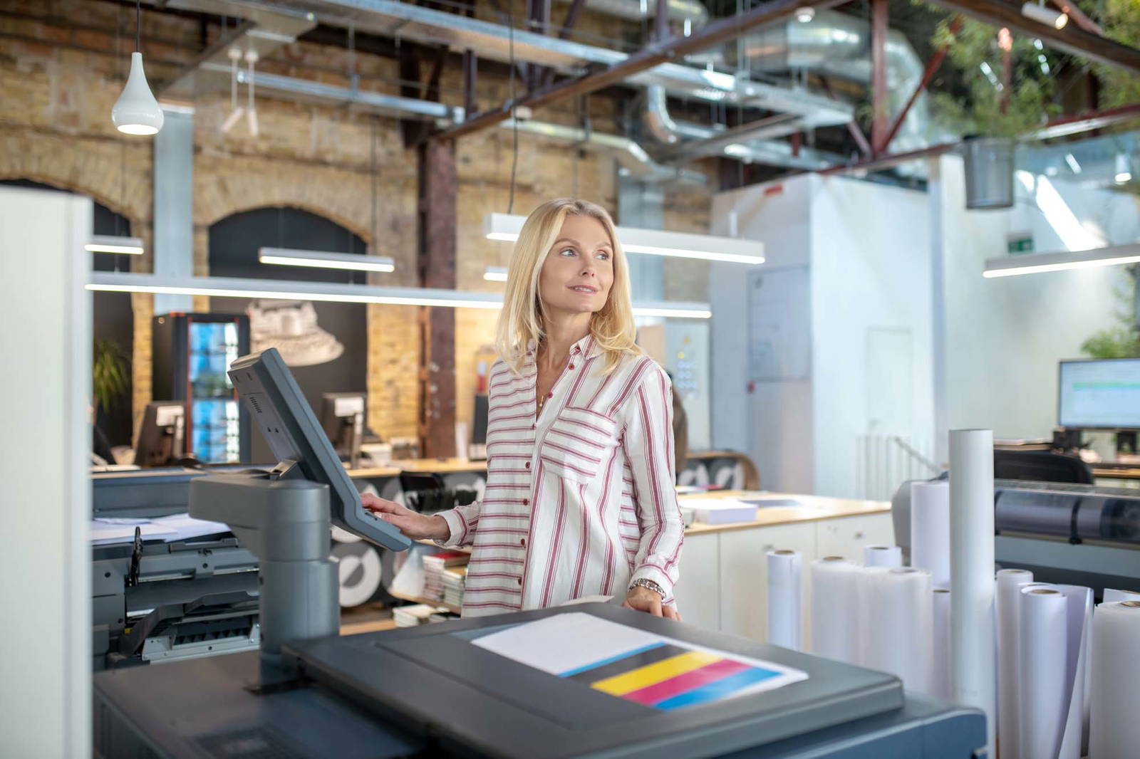 Woman working at a large office printer.