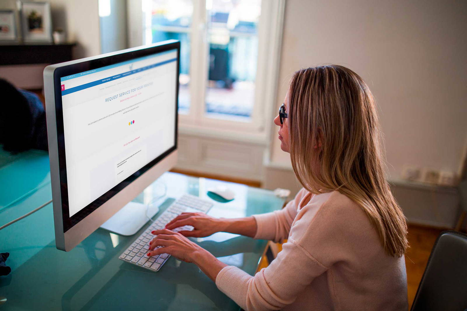 Woman working at a desk filling out our Request Service Form.