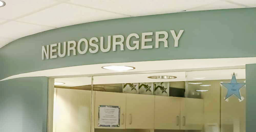 Sage green walls in a medical office displaying signage of text "NEUROSURGERY".