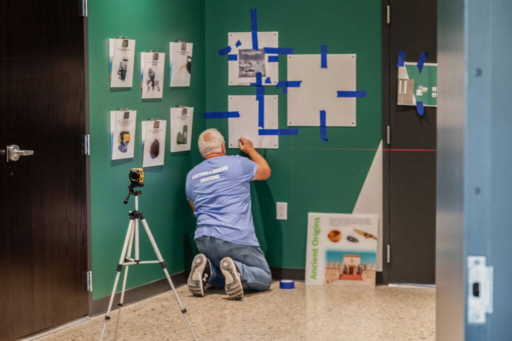 BPI Color install team is hanging a grid of images.