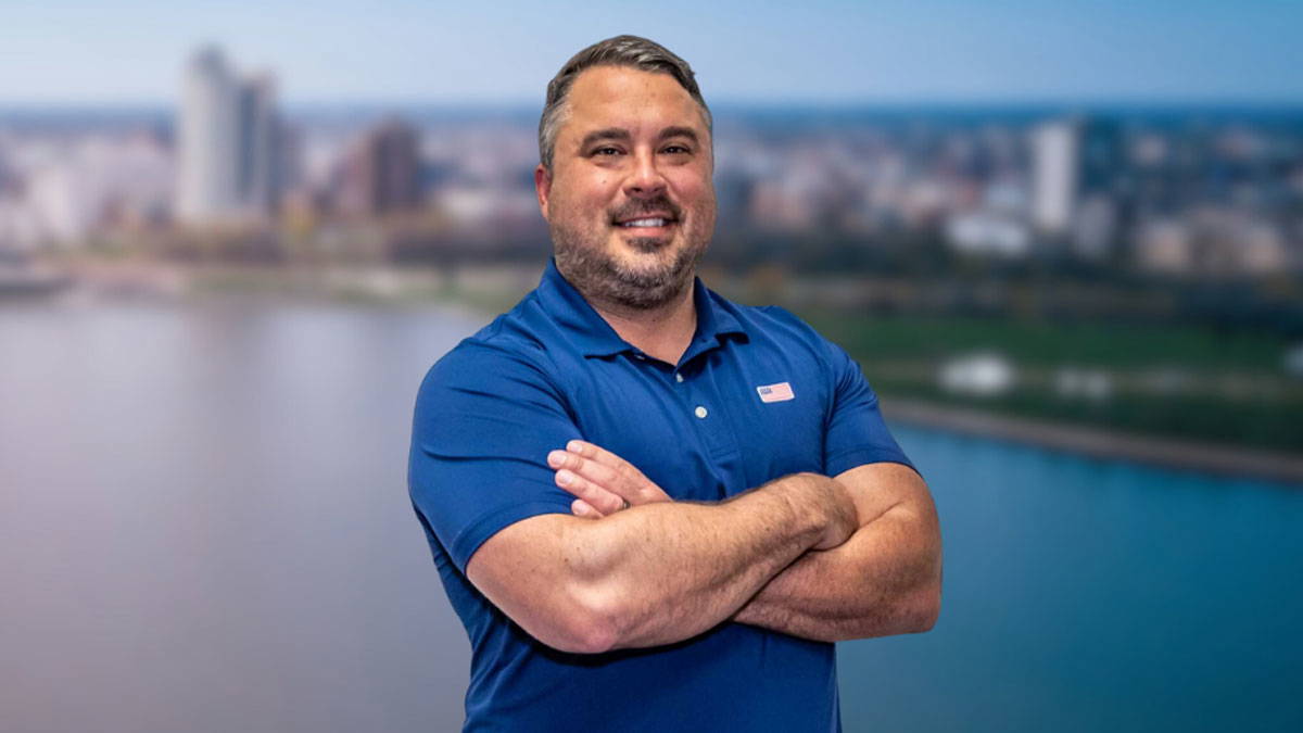 The owner of BPI Color, Clint Tornow in a blue collard shirt with arms crossed and smiling.