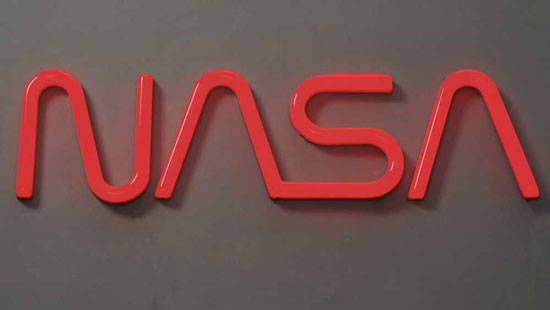 Bright red letters "NASA" on a dark gray wall.