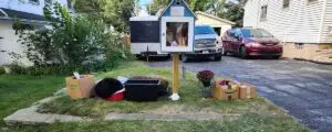 Bruno's Little Pet Pantry outside a residential home, surrounded by donations including pet beds, food, and supplies, supporting community pet needs.