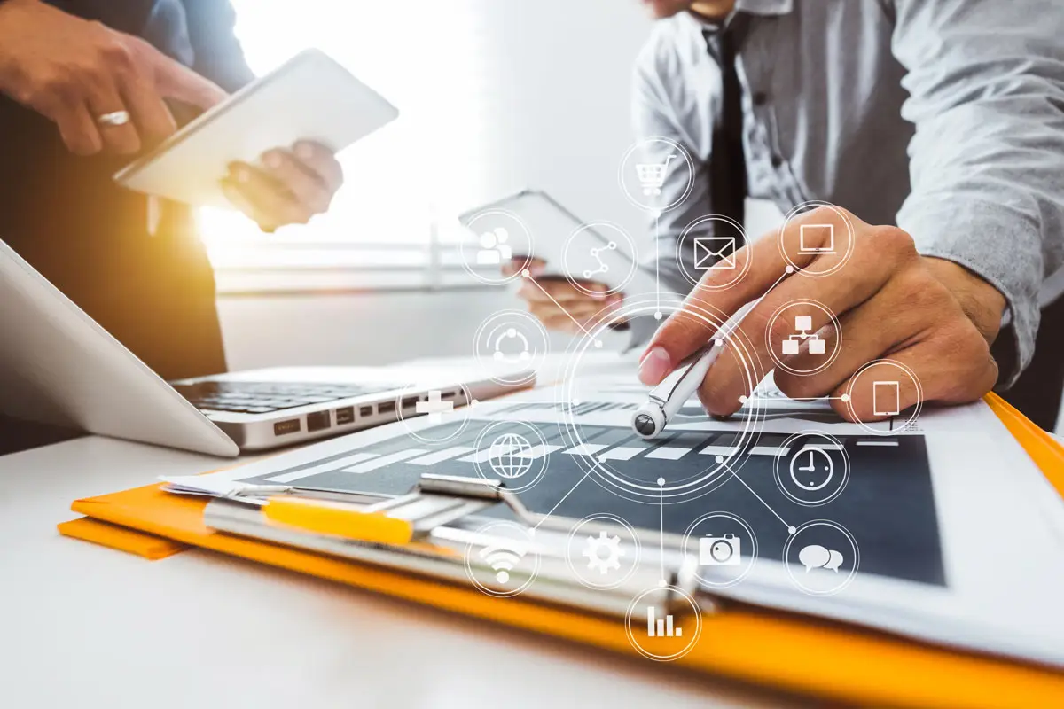 BPI Color's 2024 Year in Review 9 AI Powered business technology scene with professionals using digital tablets and stylus pens, overlaid with futuristic icons representing data and connectivity.