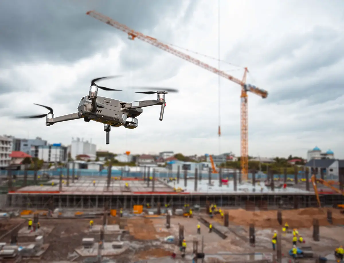 BPI Color's 2024 Year in Review 8 Drone Flying Over Construction Site capturing aerial footage above a busy job site with workers, cranes, and building materials under a cloudy sky.