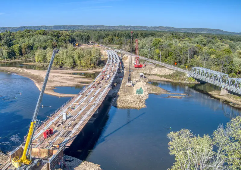 BPI Color's 2024 Year in Review 3 WIS 130 Bridge Lone Rock aerial view of active bridge construction over the Wisconsin River, featuring cranes, steel beams, and work crews in progress.