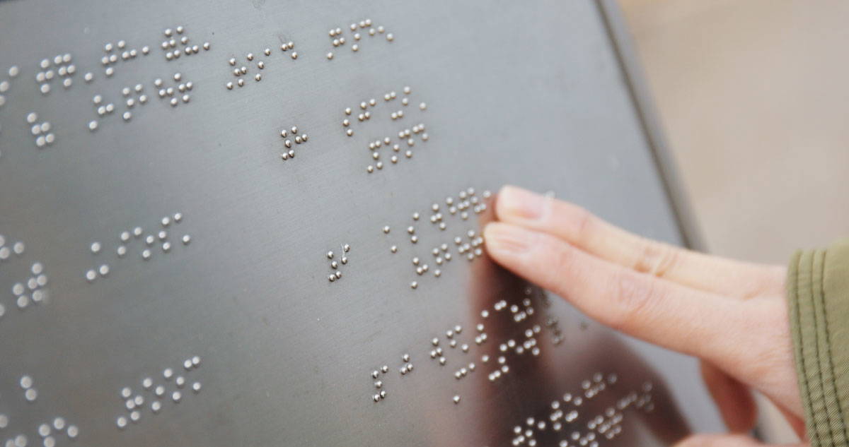 Person reading a Braille sign.