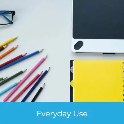 Everyday Use Promotional Products including colorful pencils, a digital tablet, spiral-bound notebook, and glasses arranged neatly on a white desk.
