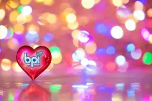 February Newsletter Banner featuring a glass red heart with the BPI Color logo in front of a colorful bokeh light background.