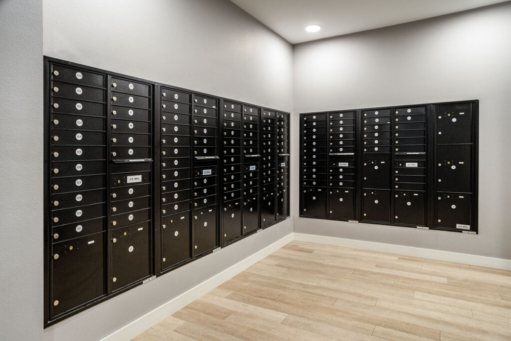 ADA Signage for Parcel Room full view of black wall-mounted mailboxes at Colorado Commons, organized with clear numbered labels for resident access.