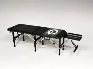 Thuli Tables custom black chiropractic table featuring the Green Bay Packers “G” logo, complete with adjustable headrest and foldable legs.