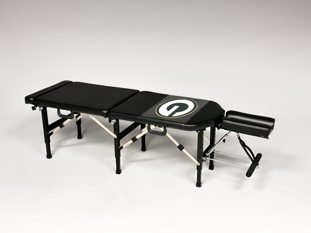 Thuli Tables full-length portable chiropractic table with custom Green Bay Packers “G” logo, featuring headrest and multiple panels.