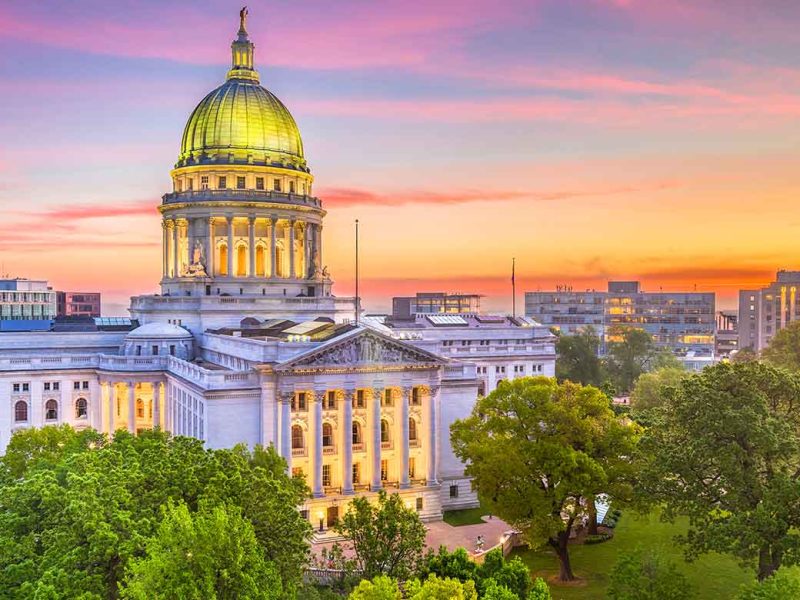 BPI Color Madison WI view of the Wisconsin State Capitol at sunset, surrounded by lush trees and city buildings in downtown Madison.
