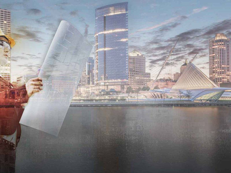 Female architect holding blueprints standing in front of Milwaukee skyline.