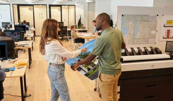 Two coworkers meeting next to a printer.